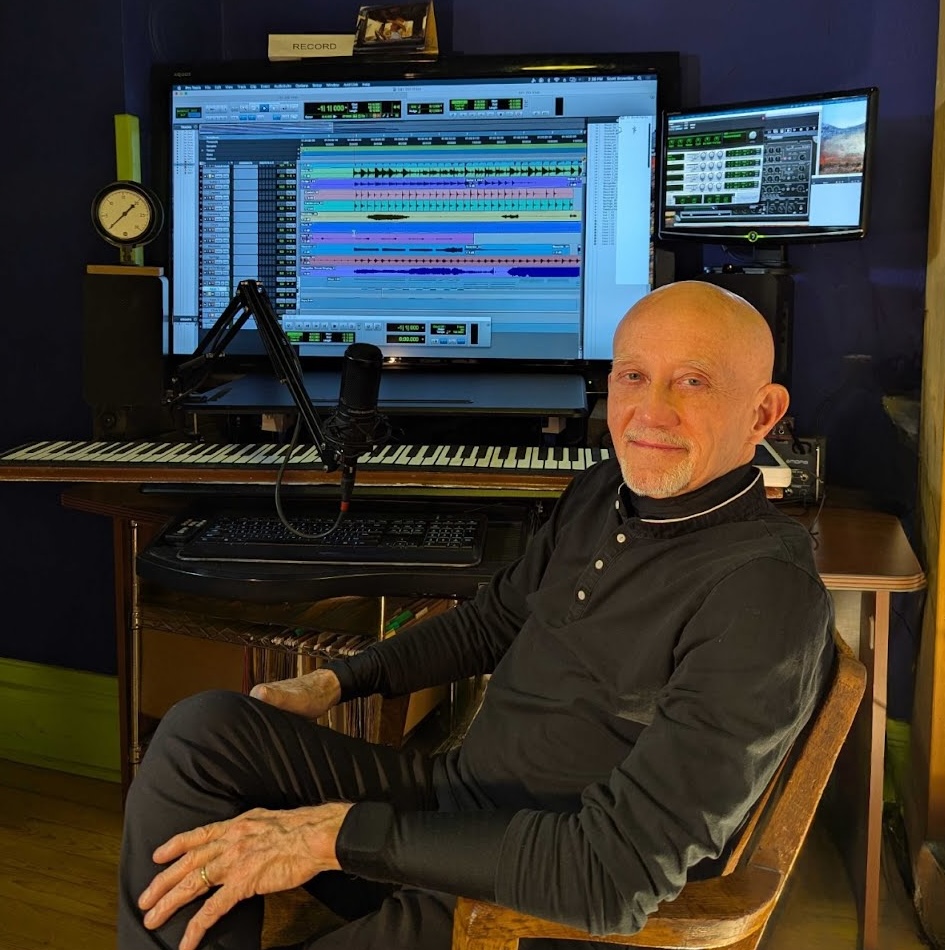 A photo of Scott Brownlee at his audio mixing setup desk